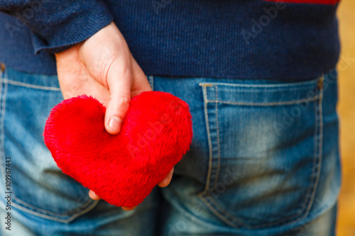 Man holding heart behing his body.