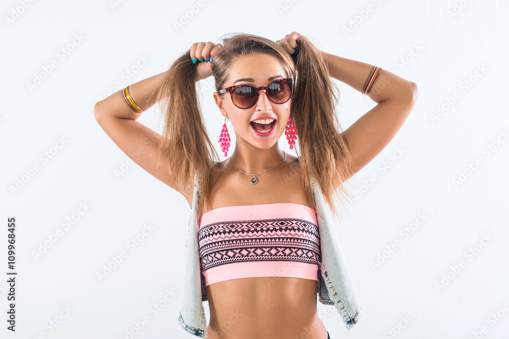 Studio shot of a young happy girl laughing, holding her hair, imitating tails hairstyle, wearing sunglasses and trendy outfit. Studio shot of a young happy girl laughing, holding her hair, imitating tails hairstyle, wearing sunglasses and trendy outfit.