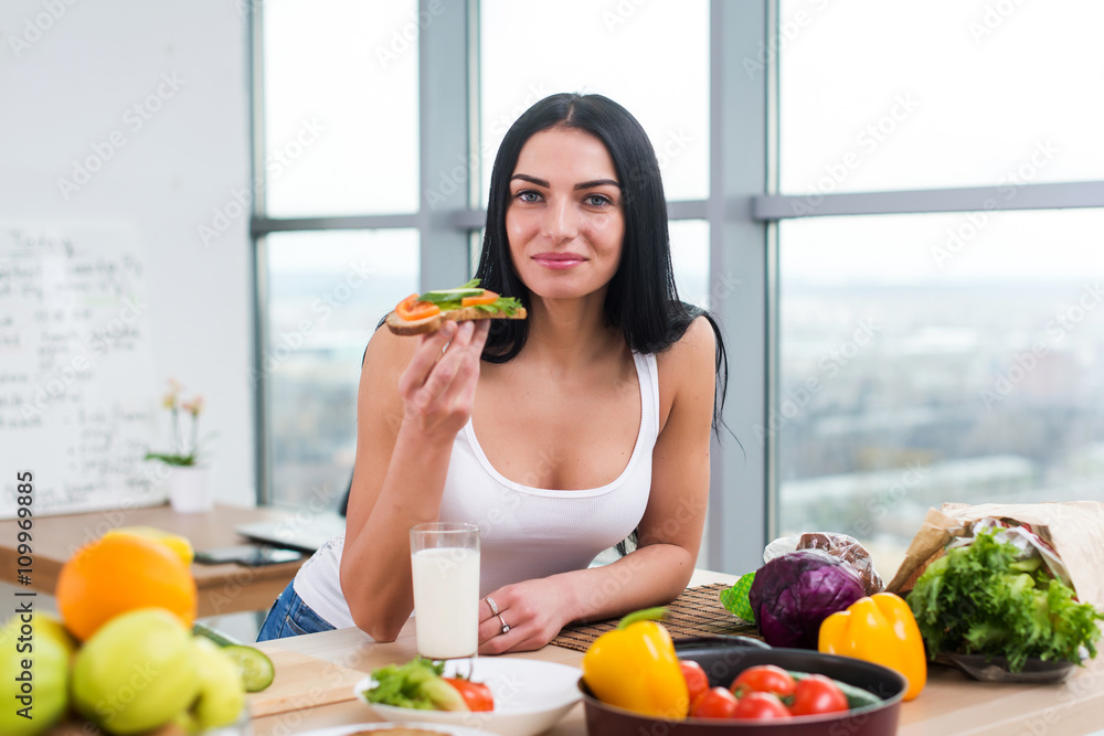 Close-up portrait of smiling woman eating diet vegetarian sandwich with vegetables for breakfast in morning, looking at camera. Close-up portrait of smiling woman eating diet vegetarian sandwich with vegetables for breakfast in morning, looking at camera.