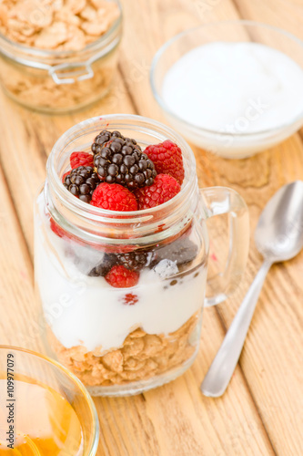 transparent jar with berries and yogurt cereals