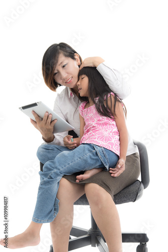 Working mother and daughter with tablet are sitting on office ch
