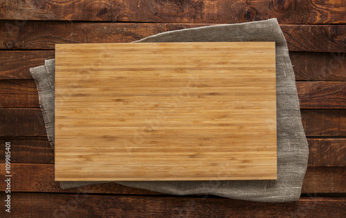 Cutting board on brown wooden table, top view