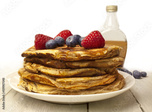 Stack of homemade pancackes with generic maple syrup bottle