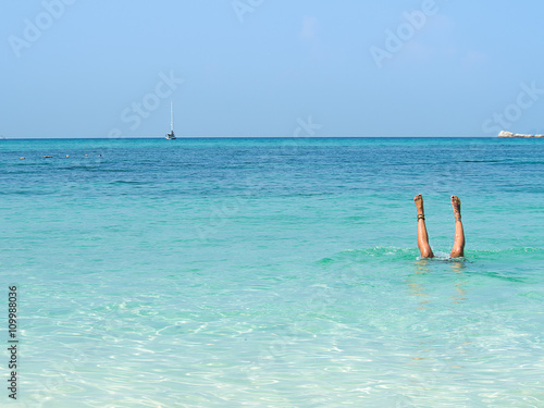 Woman feet doing a somersault underwater in the sea. Woman feet relaxing and enjoying in the sea on sunny summer day.