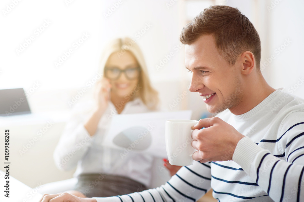 Positive guy drinking coffee at work  