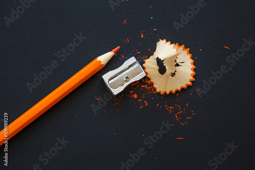 sharpener and orange pencil shavings on black