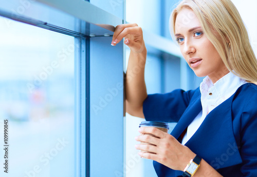 Yound woman drink coffee at office, standing 