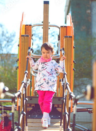 Cheerful little girl having fun at the playground