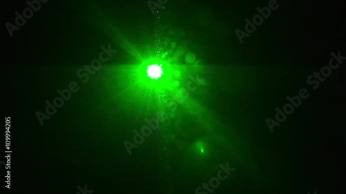 ein grüner Laser leuchte direkt in die Kamera in einem dunklen Raum photo