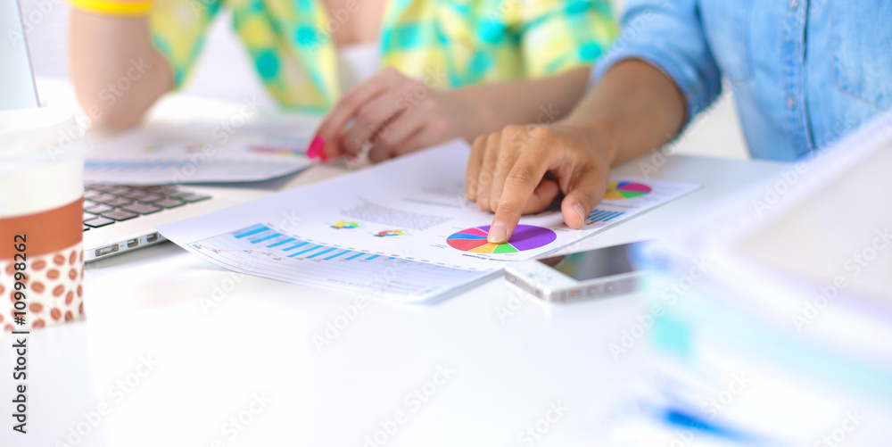 Two women working together at office, sitting on the desk Two women working together at office, sitting on the desk