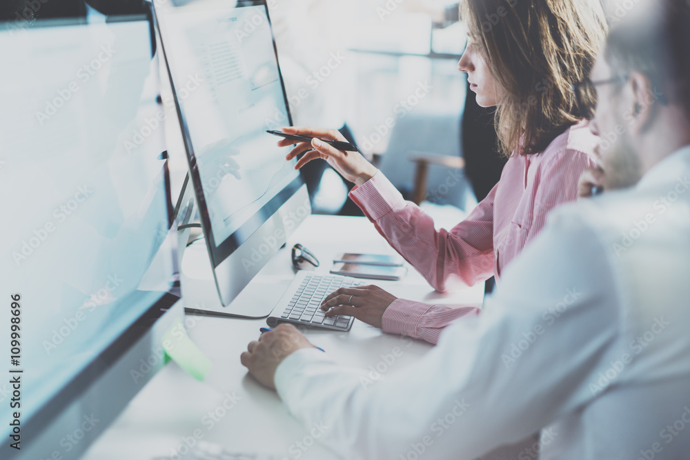 © SFIO CRACHO - Coworkers team in modern office.Project managers work new idea.Young business crew working with startup studio.Desktop computer table,showing presentation,reflection monitor.Blurred,film effect.