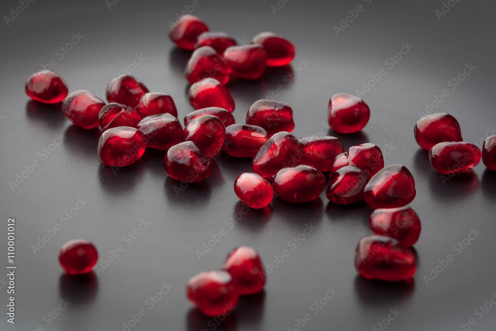 Pomegranate seeds scattered on black plate extreme closeup. Shallow depth of field. Pomegranate seeds scattered on black plate extreme closeup. Shallow depth of field.