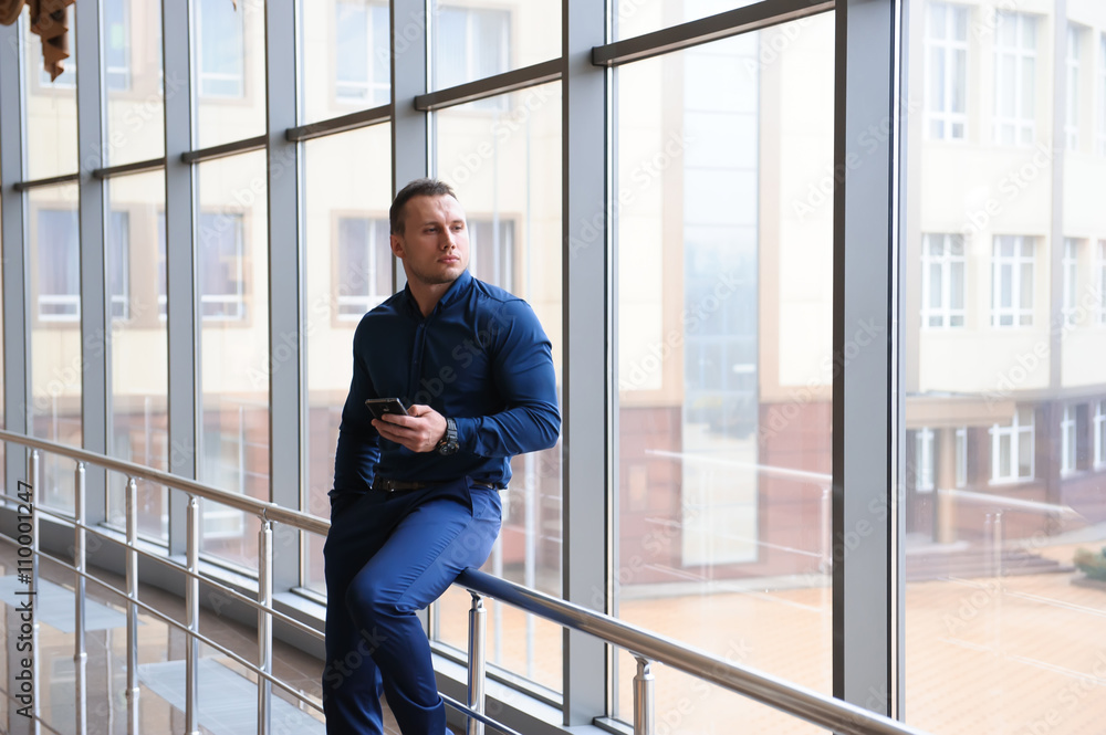 businessman looking through the phone by the window businessman looking through the phone by the window