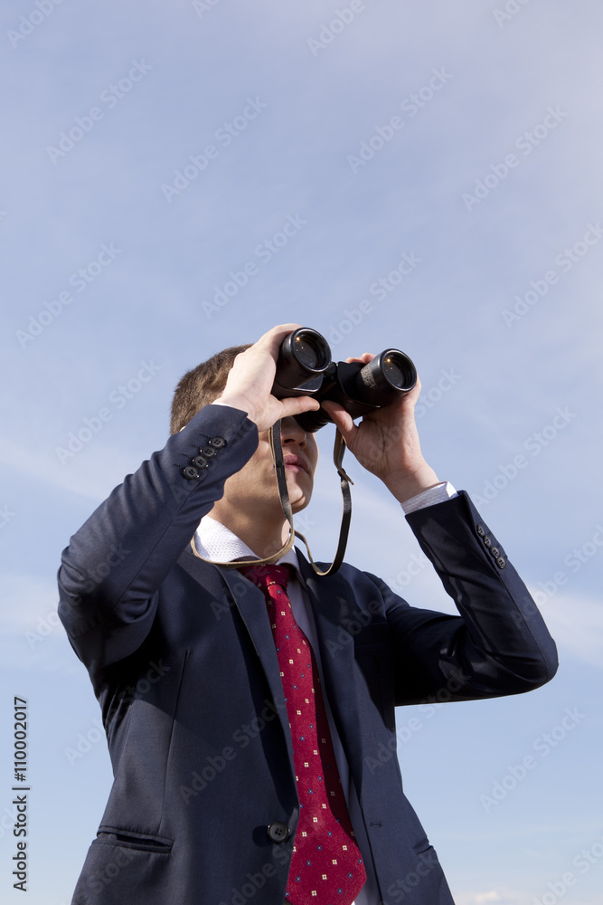 Businessman looks through a binoculars Businessman looks through a binoculars