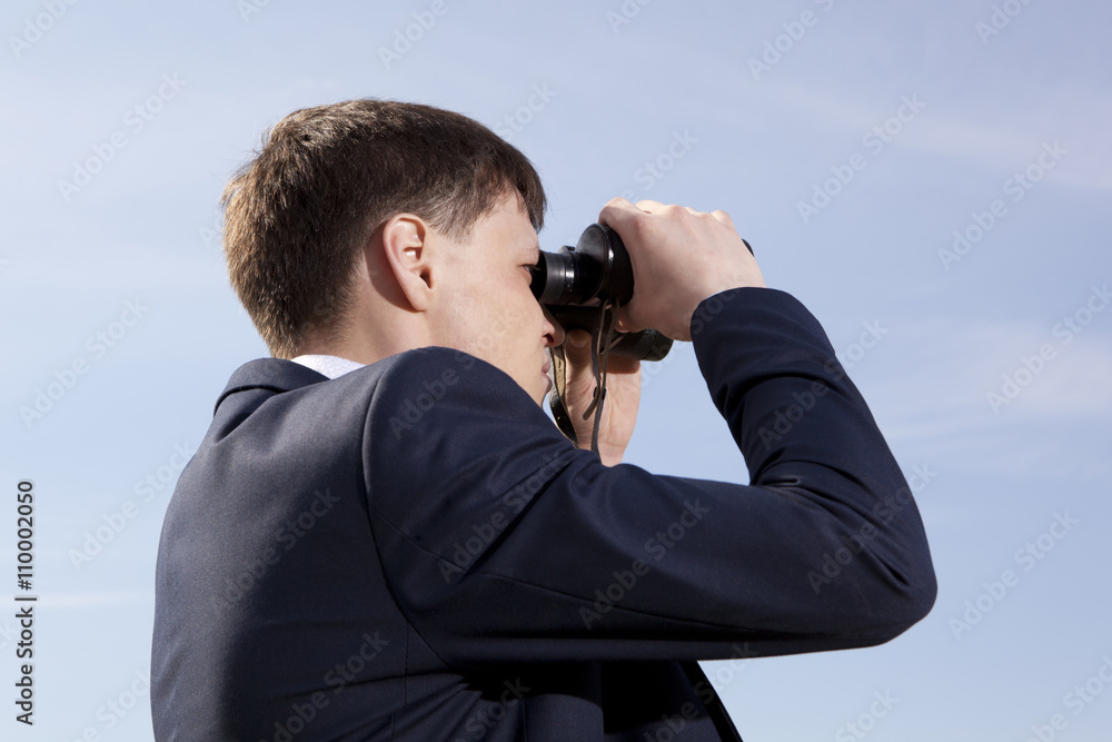 Businessman looks through a binoculars
