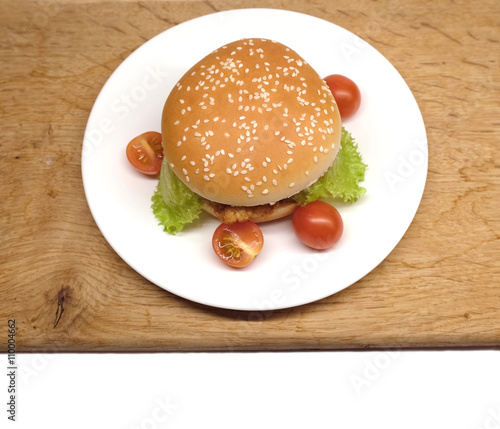 Appetizing homemade beef burger with salad and small tomatoes on white plate isolated ready to eat