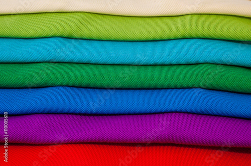 Pile of luxurious fine material 100% cotton polo shirts in various colors.
