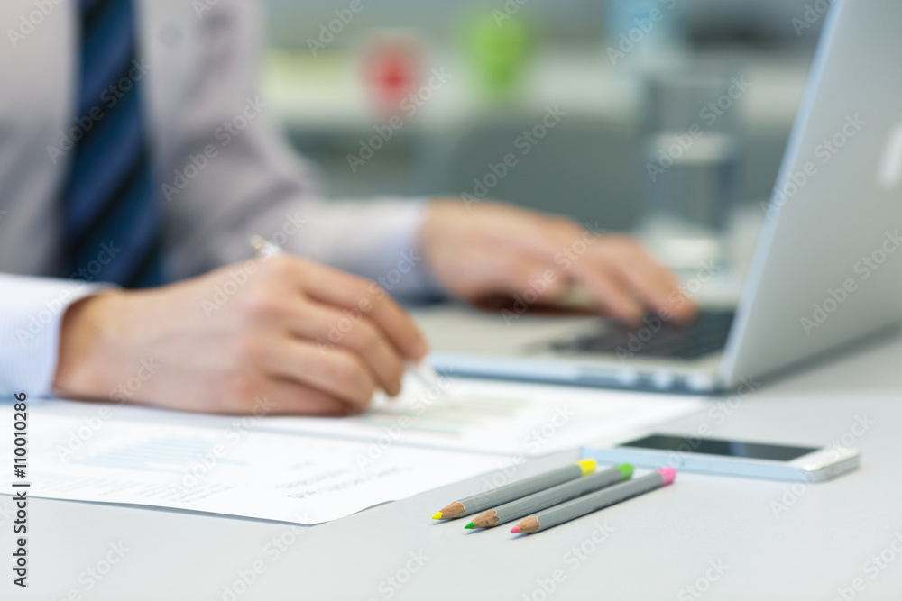 Businessman working on Laptop and printed Charts Businessman working on Laptop and printed Charts