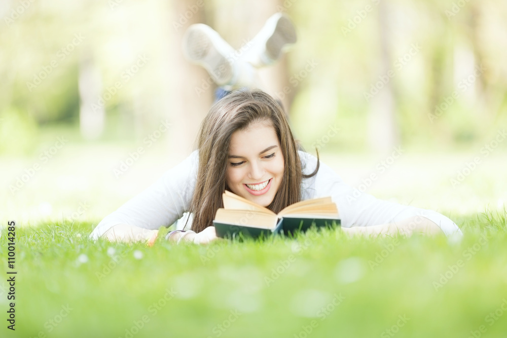 Young smiling woman reading magazine lying on grass. Young smiling woman reading magazine lying on grass.