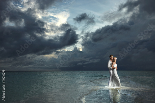 Φωτογραφία Wedding couple, bride and groom standing under threatening cloud