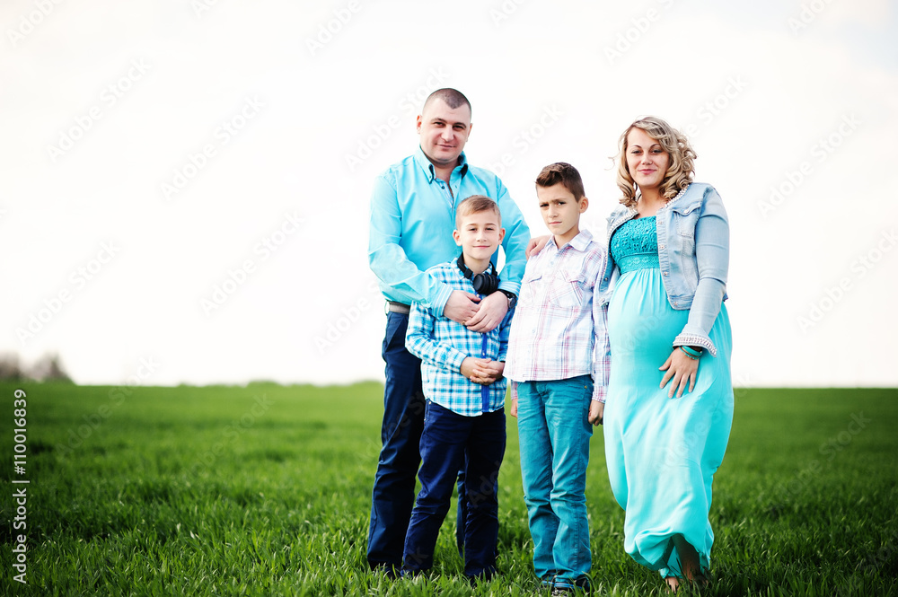 Happy pregnant family with two sons, dressed in a turquoise clot Happy pregnant family with two sons, dressed in a turquoise clot