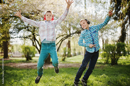 Two brother boy with headphones having fun and jump in air on pa