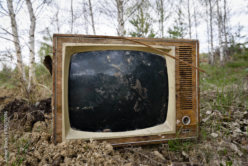 Old analog discarded television set in the forest photo