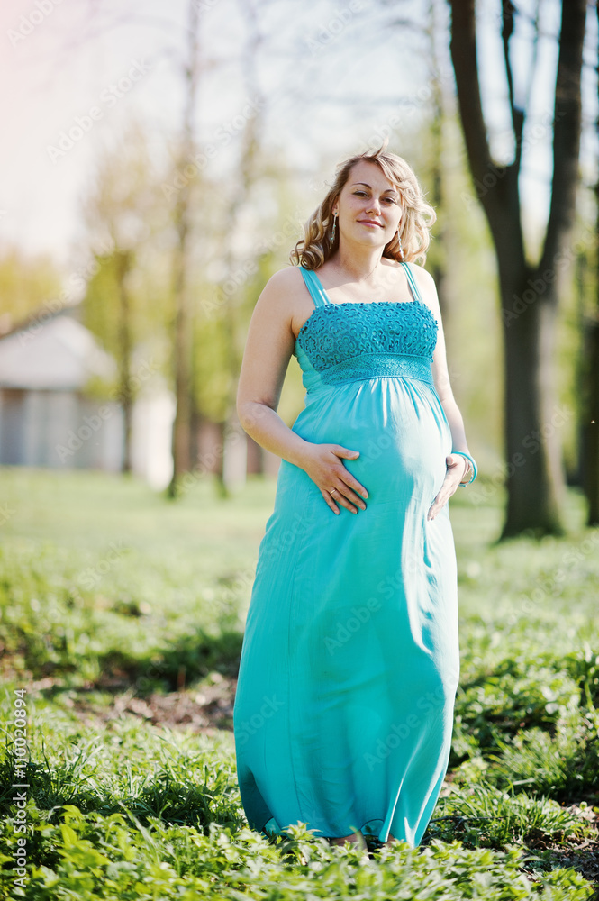 Portrait of happy pregnant woman dressed in a turquoise dress at Portrait of happy pregnant woman dressed in a turquoise dress at