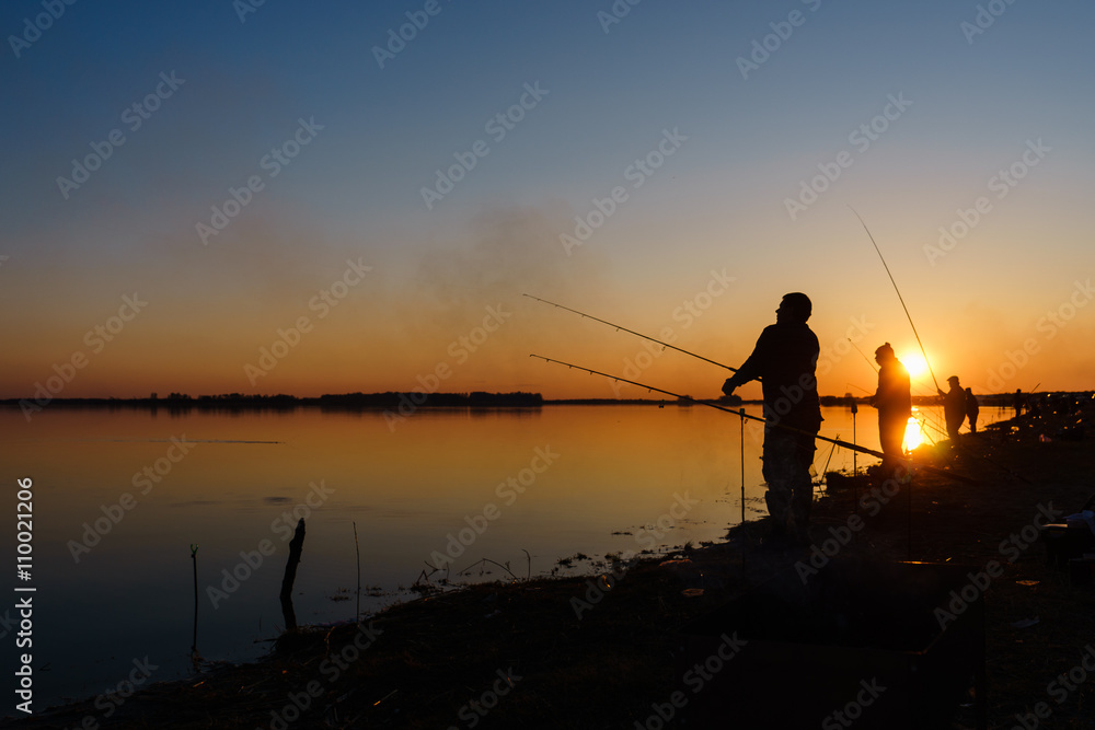 Fisherman catches fish by spinning on the lake at sunset