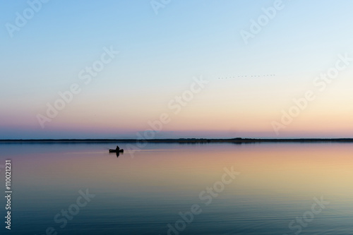 fishmonger in his traditional boat at sunrise