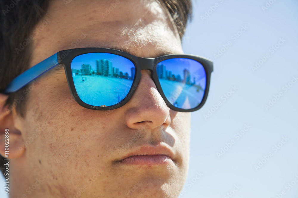 Big Close up portrait of a teenager boy wearing blue mirror sun Big Close up portrait of a teenager boy wearing blue mirror sun