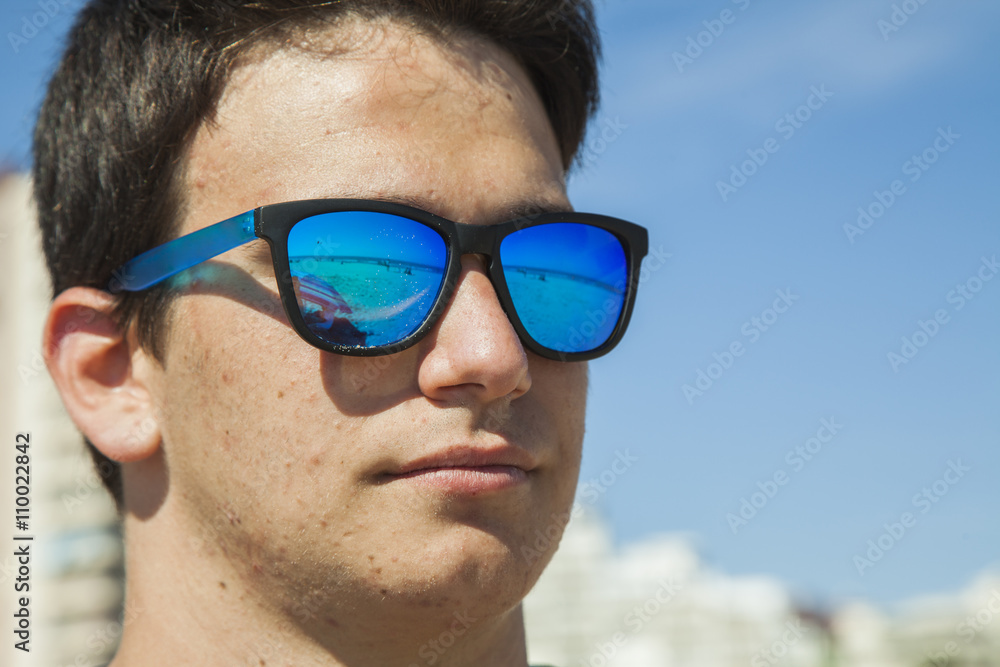 Big Close up portrait of a teenager boy wearing blue mirror sun