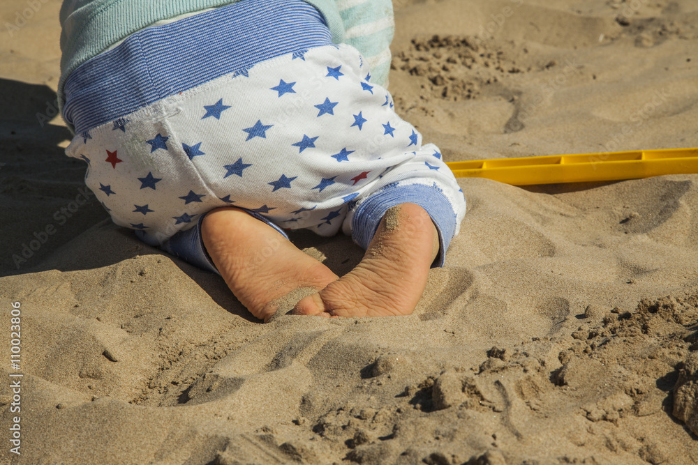 Close up baby boy playing with sand toys at the beach. Rear view Close up baby boy playing with sand toys at the beach. Rear view