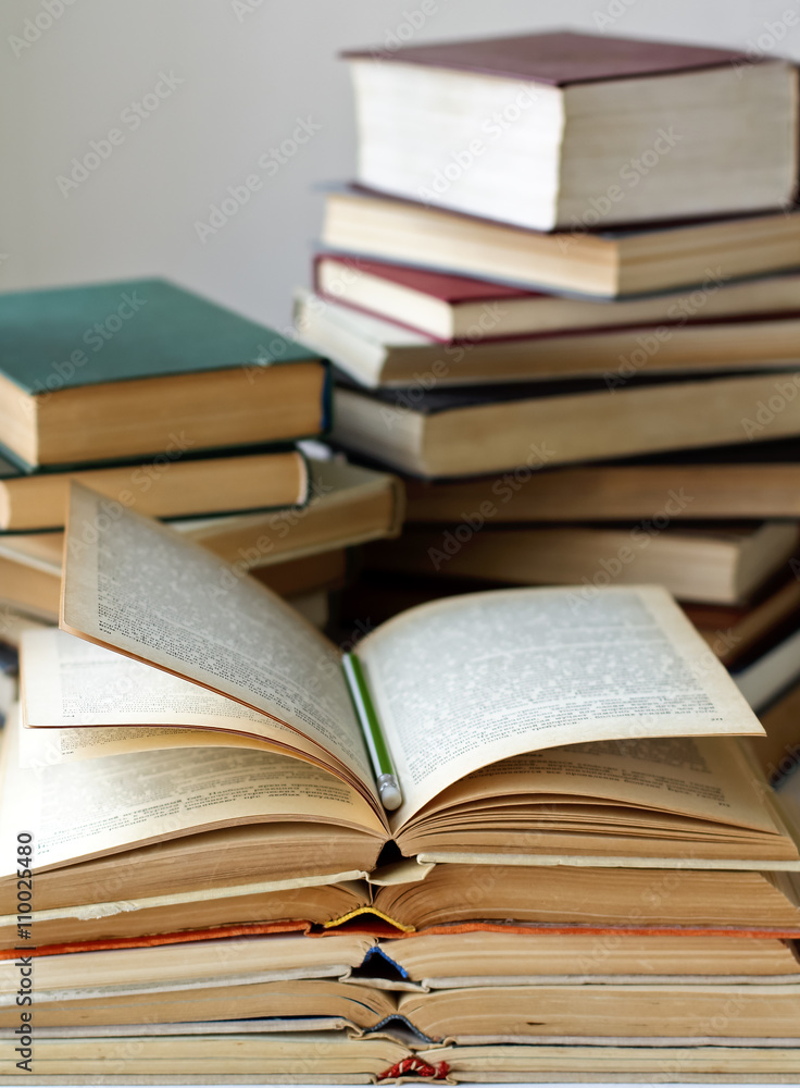 stacks of old closed and opened books and pencil. vertical stacks of old closed and opened books and pencil. vertical