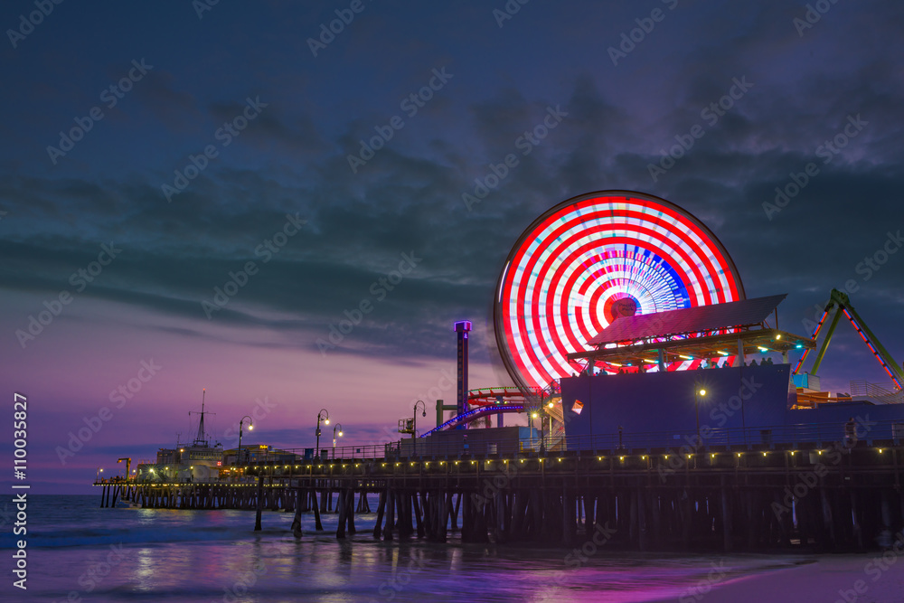 Santa Monica pier at dusk photographed with a long exposure. Focus on the ferris wheel with a purple sky in the background. 