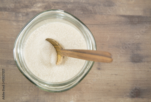 Granulated sugar in glass jars and wooden spoon