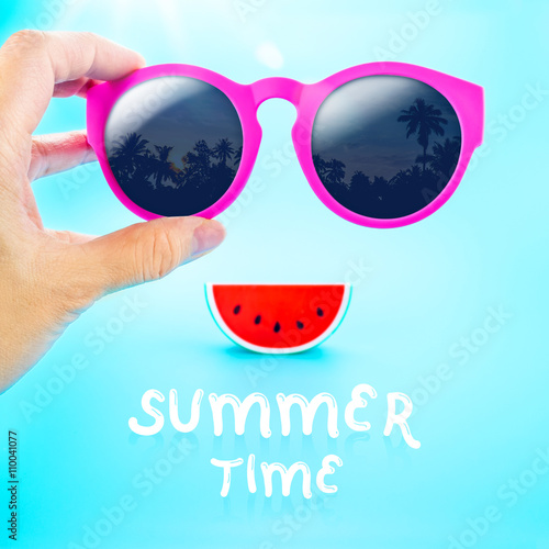 hand holding summer pink glasses with palm tree view and waterme photo