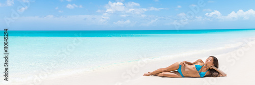 Paradise tropical vacation woman relaxing on perfect white sand beach Caribbean travel destination. Luxury living dreamy getaway Asian skincare model lying down sun tanning in secluded resort.