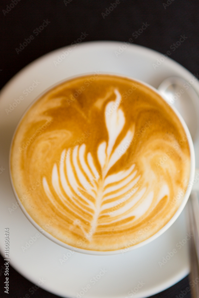 Coffee on dark background with shape of flower in the cream Coffee on dark background with shape of flower in the cream