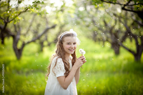 Girl blowing on a dandelion in the garden