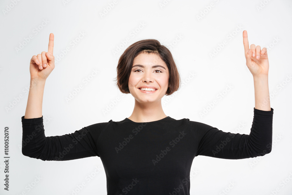 Happy woman pointing fingers up at copyspace Happy woman pointing fingers up at copyspace