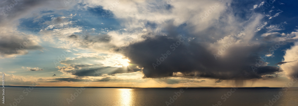 rain cloud and the sun over the sea panorama.