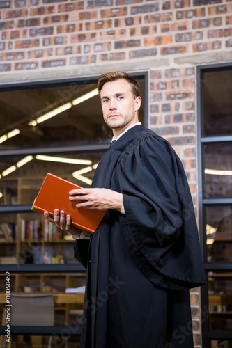 Lawyer standing near library with law book