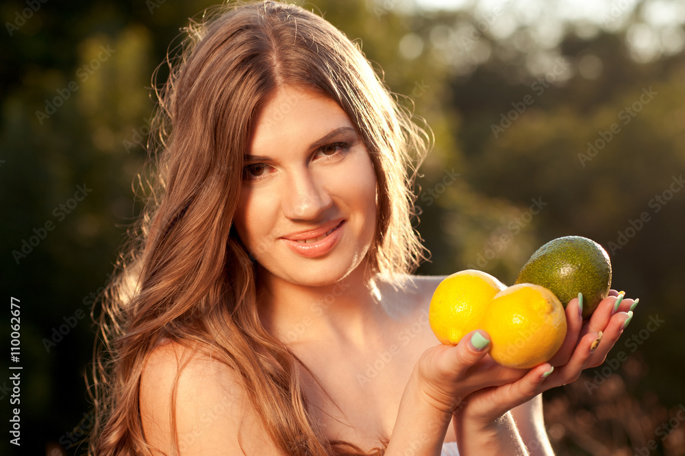 Smiling woman holding lemons and avocado outdoors closeup. Looking at camera. 20s. Healthy lifestyle. Organic food. Smiling woman holding lemons and avocado outdoors closeup. Looking at camera. 20s. Healthy lifestyle. Organic food.