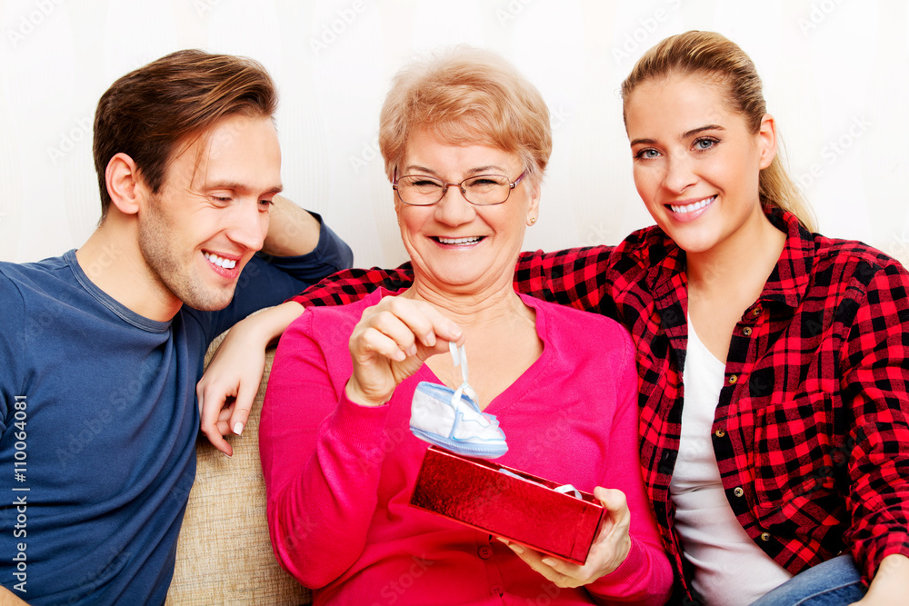 Happy family - couple with old woman who holding gift box and baby shoe Happy family - couple with old woman who holding gift box and baby shoe