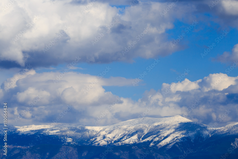 Snowy mountain range with blue sky and clouds.
