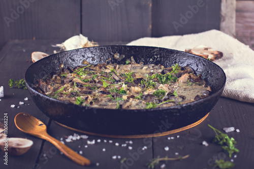 Roasted  champignons mushrooms with meat, butter, parsley and roasted garlic in black bowl. Selective focus. Healthy food concept.