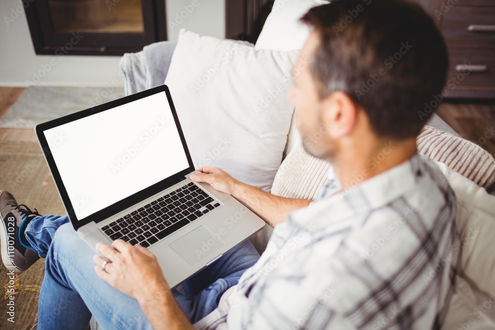 Man using laptop while sitting on sofa at home Man using laptop while sitting on sofa at home