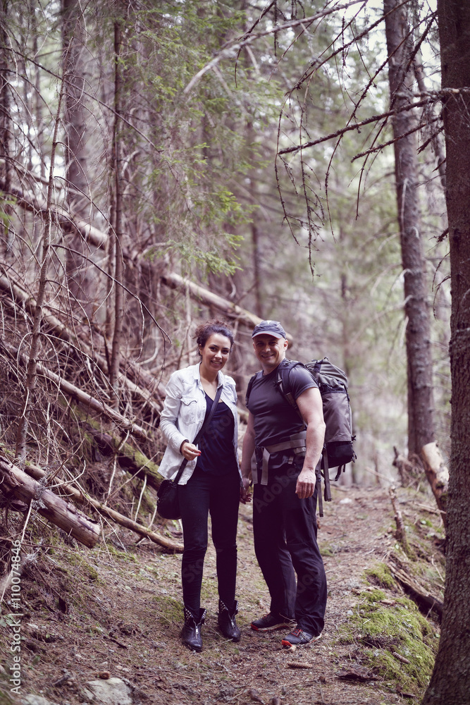 A woman and a man are trekking in the forested mountain A woman and a man are trekking in the forested mountain