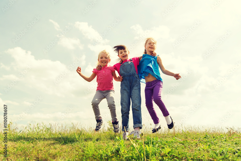 group of happy kids jumping high on green field